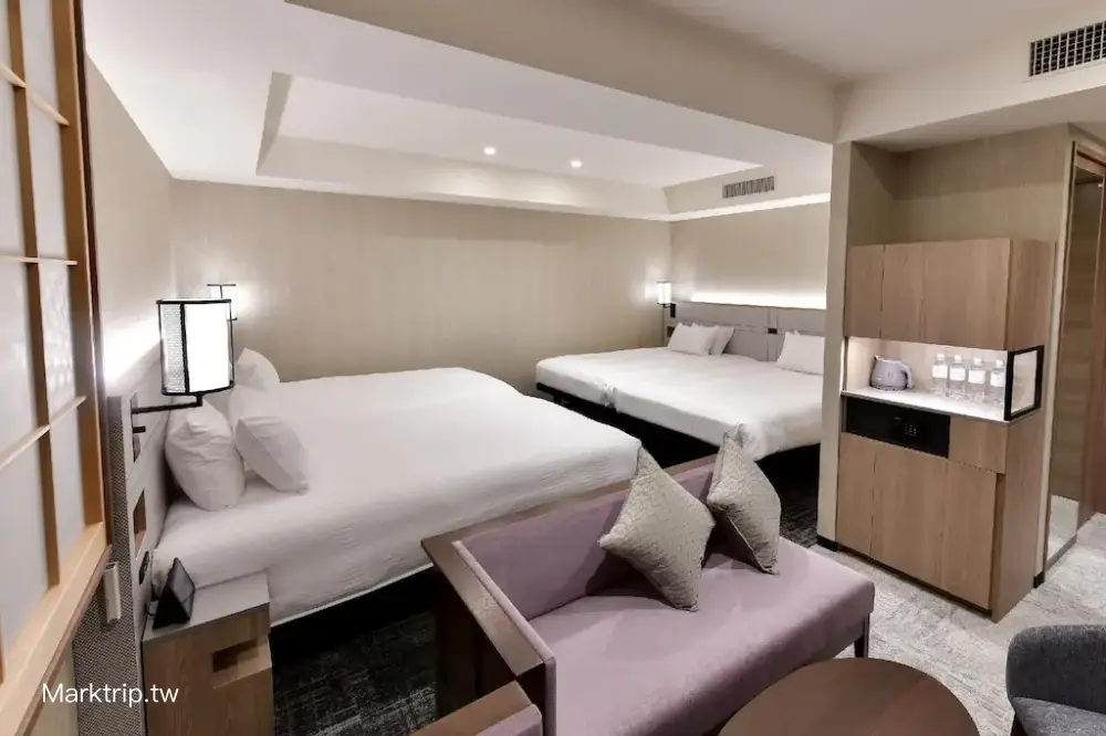 飯店內現代風格的雙人房，有大床、電視與沙發椅。