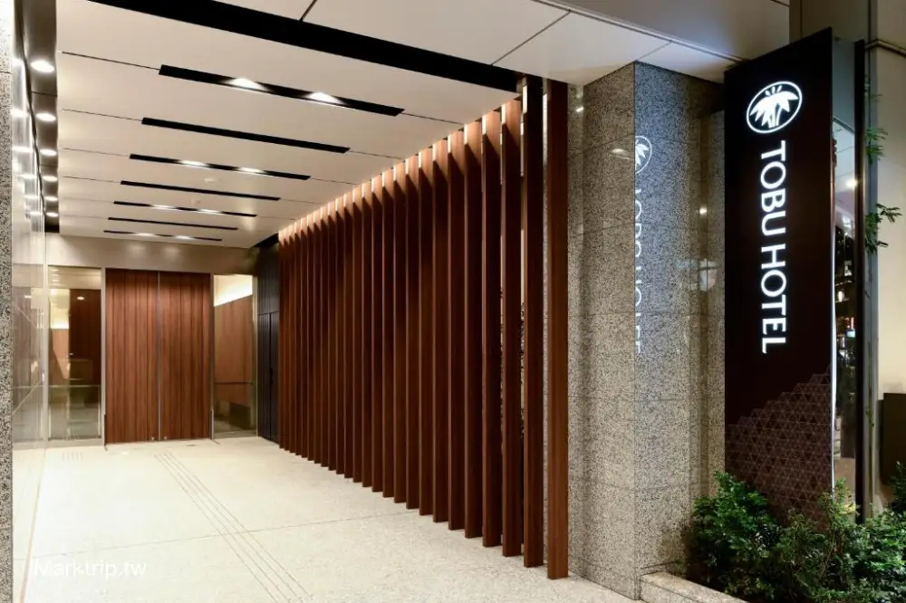 飯店一樓入口，有 TOBU HOTEL 招牌，木條裝飾牆面。